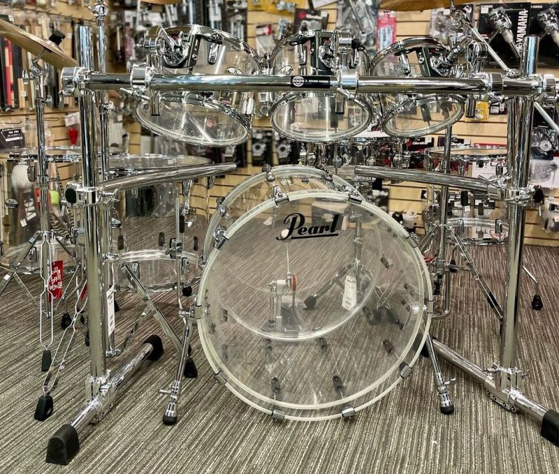 A complete Pearl drum set with a chrome finish, including a bass drum, snare drum, and a set of toms displayed on a retail floor.